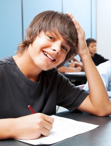 Friendly, smiling adolescent boy in school classroom.